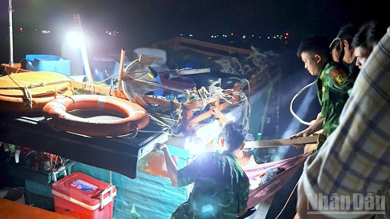 Cán bộ, chiến sĩ Đồn Biên phòng Hòn Chuối hỗ trợ đưa ông Đạt xuống tàu vào bờ tiếp tục cấp cứu, điều trị.