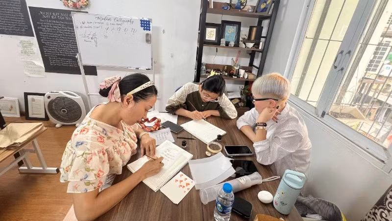 Trịnh Đỗ Hồng Thủy (giữa) hướng dẫn cho người tập viết.