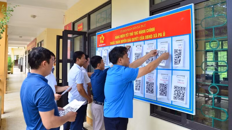 Cán bộ xã Pa Ủ triển khai niêm yết mã QR về thủ tục hành chính tại UBND xã, trụ sở được tận dụng từ trường THCS để làm việc.