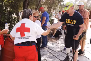 Một tình nguyện viên của dịch vụ y tế khẩn cấp tại Hy Lạp phát nước miễn phí cho du khách tại thành cổ Acropolis hôm 14/7. (Ảnh: REUTERS) 