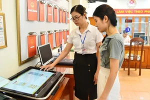 Cán bộ Ủy ban nhân dân phường Thanh Xuân Nam (quận Thanh Xuân, Hà Nội) hướng dẫn người dân thực hiện thủ tục hành chính trên môi trường mạng. (Ảnh: THỦY NGUYÊN)