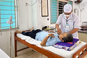 Y sĩ Nguyễn Hữu Đức điều trị cho bệnh nhân (Ảnh: NGUYỄN TRUNG)