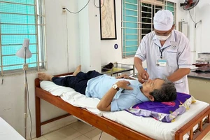 Y sĩ Nguyễn Hữu Đức điều trị cho bệnh nhân (Ảnh: NGUYỄN TRUNG)