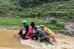Cảnh sát giao thông Hà Giang lội nước đẩy xe máy, đưa người dân qua điểm ngập an toàn.
