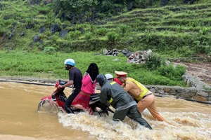 Cảnh sát giao thông Hà Giang lội nước đẩy xe máy, đưa người dân qua điểm ngập an toàn.