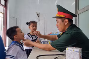 Đại úy, Bác sĩ, Thạc sĩ Lê Văn Quốc, Bệnh xá trưởng đảo Song Tử Tây thăm khám cho cháu Phan Gia Phát (4 tuổi).