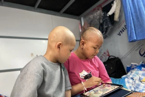 Bé Kiều Oanh và bạn xem phim hoạt hình tại phòng trọ.