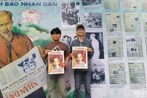 Bạn Nguyễn Đức Tân (đeo kính), sinh viên trường Cao đẳng Du lịch Hà Nội cùng bạn rất vui khi được cầm trên tay tờ báo Nhân Dân cuối tuần số đặc biệt chụp ảnh lưu niệm. (ẢNH: KIM CƯƠNG)