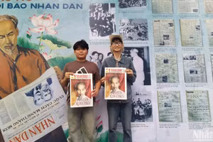 Bạn Nguyễn Đức Tân (đeo kính), sinh viên trường Cao đẳng Du lịch Hà Nội cùng bạn rất vui khi được cầm trên tay tờ báo Nhân Dân cuối tuần số đặc biệt chụp ảnh lưu niệm. (ẢNH: KIM CƯƠNG)