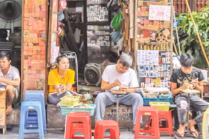 Hình ảnh ông Toàn (thứ hai từ phải sang) miệt mài khắc những con dấu gỗ đã thu hút nhiều khách du lịch khi tới phố cổ Hà Nội. 