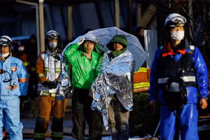 Người dân choàng chăn bạc giữ nhiệt theo dõi hoạt động cứu nạn tại thành phố Wajima, tỉnh Ishikawa, Nhật Bản, ngày 3/1/2024. (Ảnh: REUTERS)