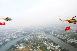 Trực thăng kéo theo cờ đỏ sao vàng và cờ Đảng ngang qua khu vực sông Đồng Nai.