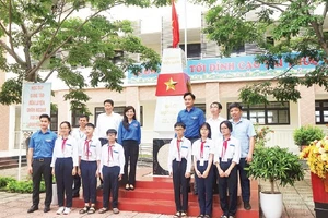 Đại biểu và các em học sinh chụp ảnh lưu niệm với Cột mốc chủ quyền biển đảo.