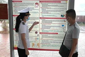 Kiểm dịch viên của Trung tâm Kiểm dịch y tế quốc tế Quảng Ninh tuyên truyền về bệnh đậu mùa khỉ tại Cửa khẩu Bắc Luân II (TP Móng Cái) cho các chủ xe. (Ảnh NGUYỄN HOA) 