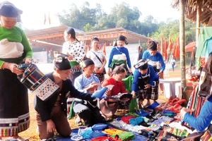 Một hàng thổ cẩm bên đường, ngoài những tấm thổ cẩm còn bán tóc giả và khăn.