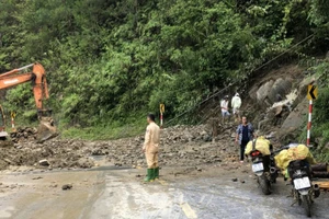 Lực lượng Cảnh sát giao thông cùng lực lượng chức năng khắc phục một điểm sạt lở trên Quốc lộ 32. Ảnh: Thái Sơn