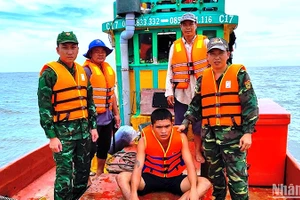 Nạn nhân Minh (ngồi) bị trôi dạt trên biển được Bộ đội Biên phòng Cà Mau cứu vớt đưa vào bờ an toàn. 