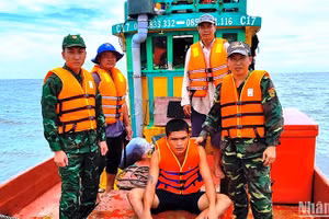 Nạn nhân Minh (ngồi) bị trôi dạt trên biển được Bộ đội Biên phòng Cà Mau cứu vớt đưa vào bờ an toàn. 