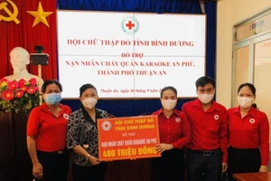 Chủ tịch Hội Chữ thập đỏ tỉnh Bình Dương Nguyễn Thị Lệ Trinh (thứ ba từ phải sang) trao tiền hỗ trợ nạn nhân vụ cháy cho lãnh đạo Ủy ban nhân dân thành phố Thuận An.