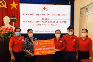 Chủ tịch Hội Chữ thập đỏ tỉnh Bình Dương Nguyễn Thị Lệ Trinh (thứ ba từ phải sang) trao tiền hỗ trợ nạn nhân vụ cháy cho lãnh đạo Ủy ban nhân dân thành phố Thuận An.