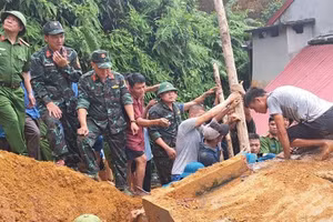 Lực lượng cứu hộ và người dân khẩn trương cứu hộ anh Lương Văn Ba bị mắc kẹt do sạt lở đất. (Ảnh: HẢI CHUNG)