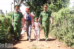 Cán bộ Công an xã Ea Sol hỗ trợ người dân địa phương đưa trẻ tới trường.