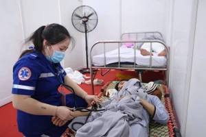 Nhân viên y tế chăm sóc người dân bị say nắng. (Ảnh: THẾ ANH)