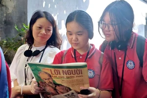 Cô giáo và học sinh trường THCS Chu Văn An (Tây Hồ, Hà Nội) đọc Báo Nhân Dân trong không gian Di tích Nhà tù Hỏa Lò.