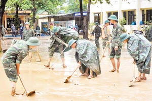 Các chiến sĩ Bộ Tư lệnh Quân khu 4 dọn bùn đất tại Trường tiểu học và Trung học cơ sở Cam Tuyền, huyện Cam Lộ (Quảng Trị). (Ảnh NGUYỄN DO) 