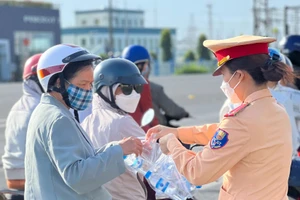 Nữ chiến sĩ Cảnh sát giao thông Công an tỉnh Đồng Nai phát nước suối, khăn lạnh cho người dân.