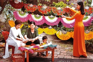 Bà Nguyễn Thị Tuấn (thứ hai, từ trái sang) giới thiệu cách làm quạt với du khách.