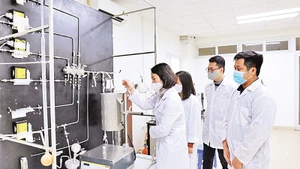 GS,TS Lê Minh Thắng cùng các cộng sự trong phòng thí nghiệm bên sơ đồ công nghệ xử lý khí thải. Ảnh: Ngô Hà
