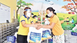 Nhân viên Công ty CP Vàng bạc đá quý Phú Nhuận (PNJ) hỗ trợ người dân tại “Siêu thị mini 0 đồng” trên địa bàn Hà Nội. Ảnh: Thủy Nguyên 