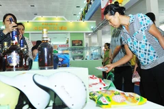 Người tiêu dùng xem các sản phẩm hàng nhái được quản lý thị trường trưng bày. Ảnh: NAM ANH