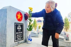 Một người vợ đang chăm sóc bia mộ của chồng. Ảnh: KHOA ĐÌNH
