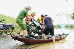 Công an xã Lam Thành (Nghệ An) hỗ trợ người dân vận chuyển xe máy lên đê tránh lũ.