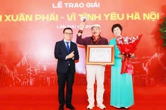 Nhà báo Lê Quốc Minh, Ủy viên Trung ương Đảng, Tổng Biên tập Báo Nhân Dân, Phó Trưởng ban Tuyên giáo và Dân vận Trung ương, Chủ tịch Hội Nhà báo Việt Nam và nhà báo Vũ Việt Trang, Tổng Giám đốc TTXVN trao Giải thưởng Lớn - Vì tình yêu Hà Nội cho nhạc sĩ Trần Tiến. Ảnh: PHAN PHƯƠNG