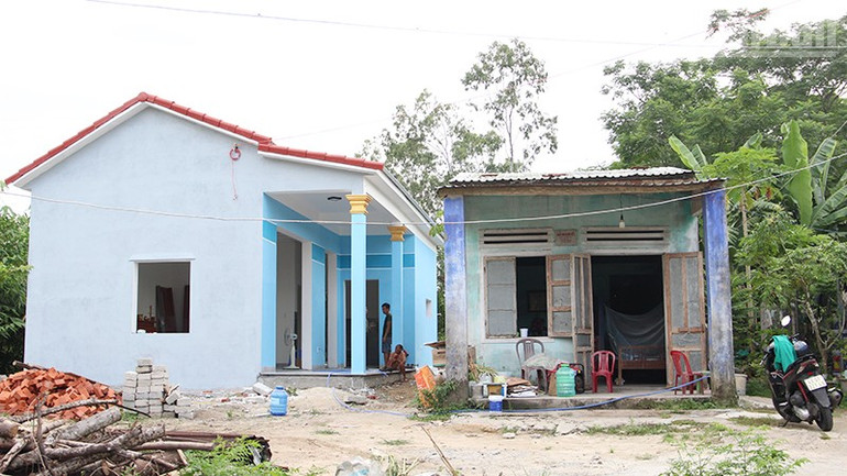 Ngôi nhà mới đang hoàn thiện của bà Nhàn bên cạnh nhà cũ đã xuống cấp. ndo_tr_nha-tam.jpg