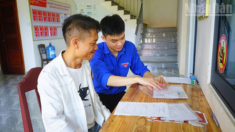 Sinh viên tình nguyện hỗ trợ người dân xã Sông Kôn đến làm thủ tục hành chính. ndo_tr_song-kon.jpg