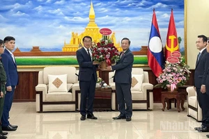 Đại sứ Nguyễn Minh Tâm trao lẵng hoa tươi thắm tới đồng chí Bounleua Phandanouvong, Trưởng Ban Đối ngoại Trung ương Đảng Nhân dân Cách mạng Lào. (Ảnh: Cộng tác viên)