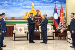 Đại sứ Nguyễn Minh Tâm trao lẵng hoa tươi thắm tới đồng chí Bounleua Phandanouvong, Trưởng Ban Đối ngoại Trung ương Đảng Nhân dân Cách mạng Lào. (Ảnh: Cộng tác viên)