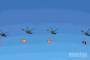 Đội hình máy bay trực thăng mang cờ Đảng, cờ Tổ quốc Lào trên bầu trời quảng trường That Luang. (Ảnh: DUY TOÀN)