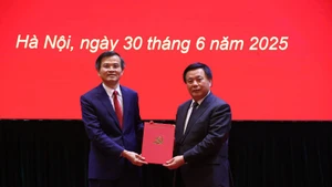 Đồng chí Nguyễn Xuân Thắng, Ủy viên Bộ Chính trị, Giám đốc Học viện Chính trị quốc gia Hồ Chí Minh, Chủ tịch Hội đồng Lý luận Trung ương trao quyết định của Bộ Chính trị về công tác cán bộ cho đồng chí Đoàn Minh Huấn.