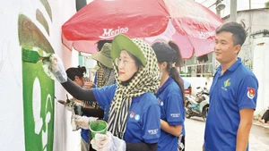 Sinh viên tình nguyện Trường đại học Giao thông vận tải Phân hiệu Thành phố Hồ Chí Minh vẽ tranh cổ động tại hẻm 74 đường làng Tăng Phú (phường Tăng Nhơn Phú).