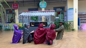 Giáo viên và lực lượng tại chỗ di chuyển đồ dùng học tập ra khỏi vùng ngập tại trường Tiểu học Sông Cầu. (Ảnh: KHÁNH LINH)