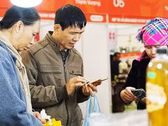 Người dân dùng điện thoại để truy xuất thông tin các sản phẩm nông sản. Ảnh: NAM ANH