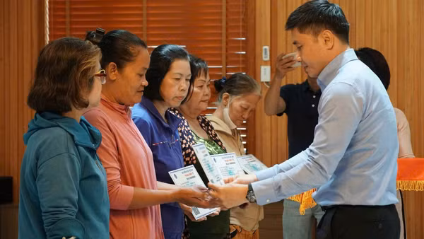 Ông Trần Dũng Hà, Phó Giám đốc Bảo hiểm xã hội Thành phố Hồ Chí Minh trao thẻ Bảo hiểm y tế cho phụ nữ có hoàn cảnh khó khăn, giúp họ có điều kiện khám chữa bệnh khi ốm đau.