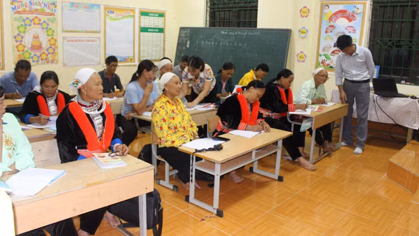 Cô giáo hướng dẫn học viên viết chữ tại lớp xóa mù ở thôn Nặm Sai, xã Bằng Thành. 