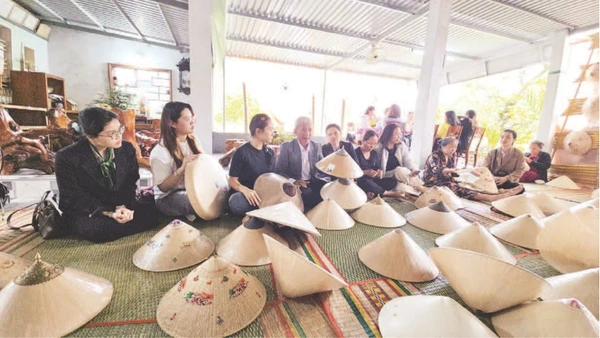 Du khách tìm hiểu các công đoạn chế tác nón ngựa tại cơ sở của Nghệ nhân Ưu tú Đỗ Văn Lan.