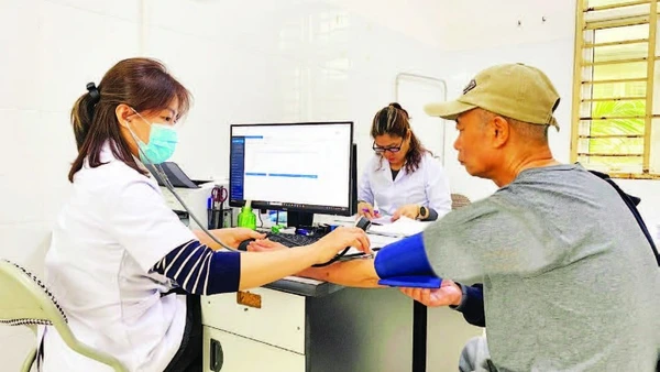 Các bác sĩ tại Trạm Y tế Long Biên khám sức khỏe cho người dân và sử dụng hệ thống dữ liệu bệnh án điện tử.